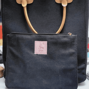 Black handbag with tan handles and a front zipper pocket on display.