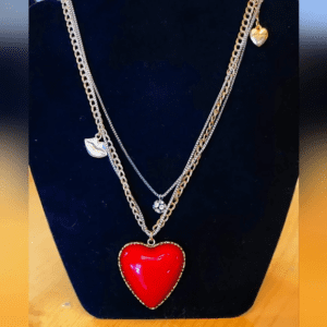 Layered silver necklaces featuring a red heart pendant.