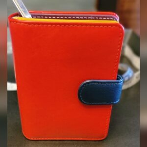 Bright orange notebook with a blue clasp on a wooden surface.