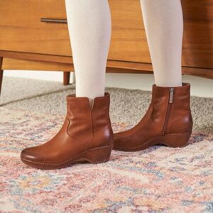 Brown leather ankle boots worn with white leggings indoors.