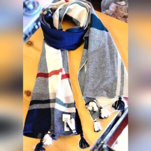 Stylish scarf with blue, gray, white, and red stripes on a wooden surface.
