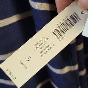 Clothing tag showing size, price, and barcode on a striped garment.