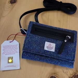 A handmade felt pouch with a zipper and a tag on a wooden surface.
