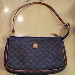 A stylish navy blue handbag with a brown strap and a circular gold emblem.
