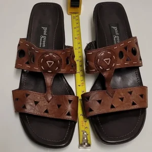 Pair of brown leather sandals with cut-out designs and a measuring tape.