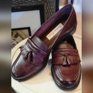 Pair of polished brown leather loafers with tassel and fringe details.