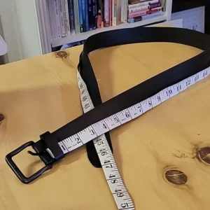 A black belt with a tape measure on a wooden table.