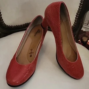 Pair of red textured high heels on a white surface.