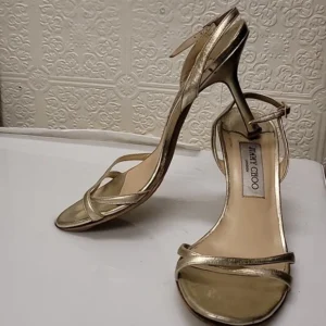 Elegant gold high-heeled sandal with ankle strap.