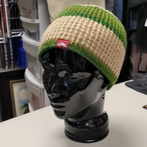 Green and beige knitted beanie displayed on a black mannequin head.